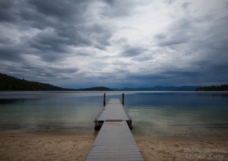 Idaho, North, Coolin. A dock extends over calm water under stormy skies at the Indian Creek Unit of Priest Lake State Park.