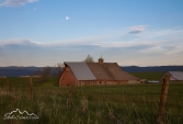 Idaho, North Central, Grangeville. Soft evening light on a faded red barn underneath an almost full moon in May.